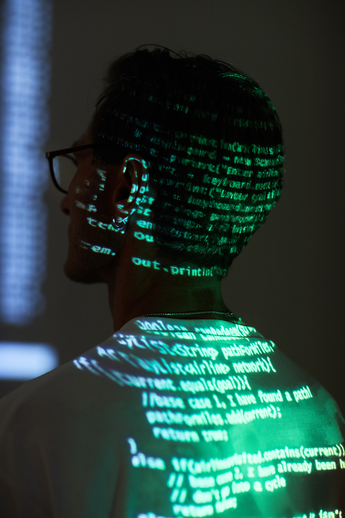 Man with computer codes shining on his head and back